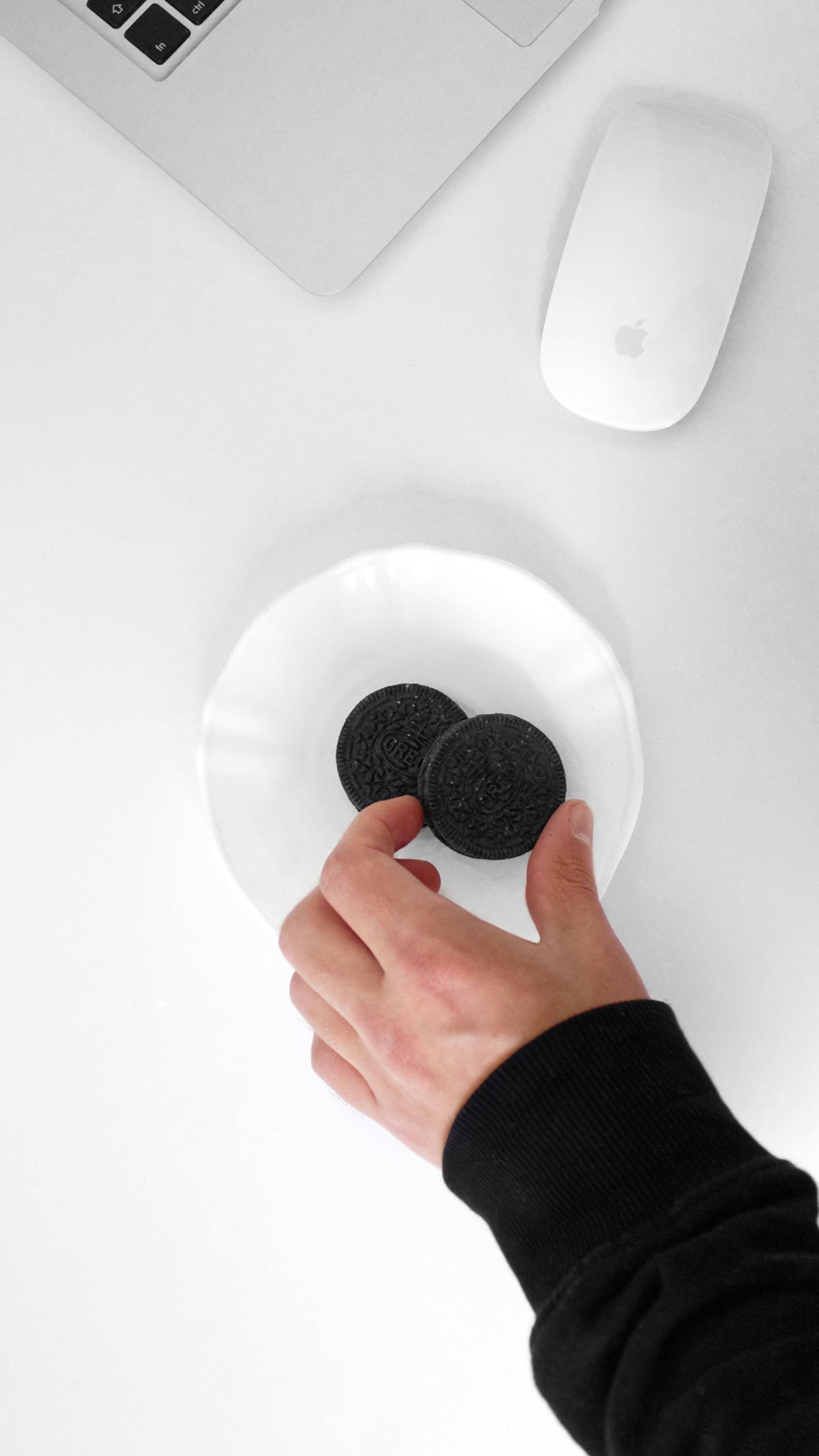 Hands near a laptop and mouse on a minimalist white desk